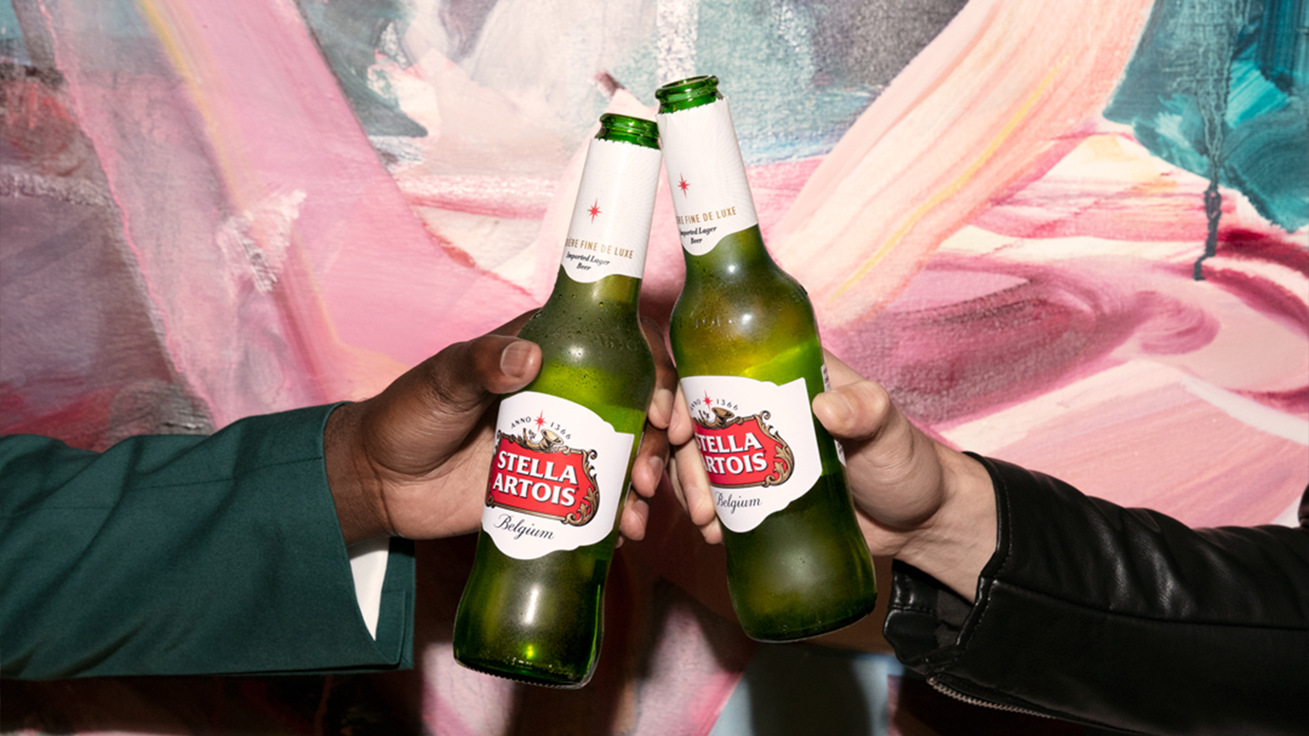 Two people clinking together bottles of Stella Artois Lager